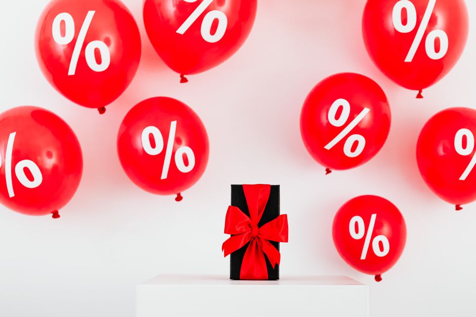 Red balloons with percent symbols and a gift box create a festive sale theme.