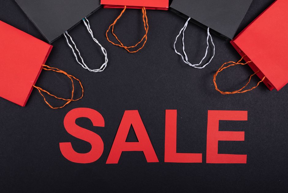 Top view of red and black shopping bags with sale text on a black background.