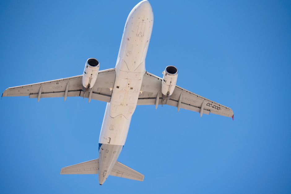 A commercial airplane flying overhead with a clear blue sky in Santiago, Chile.