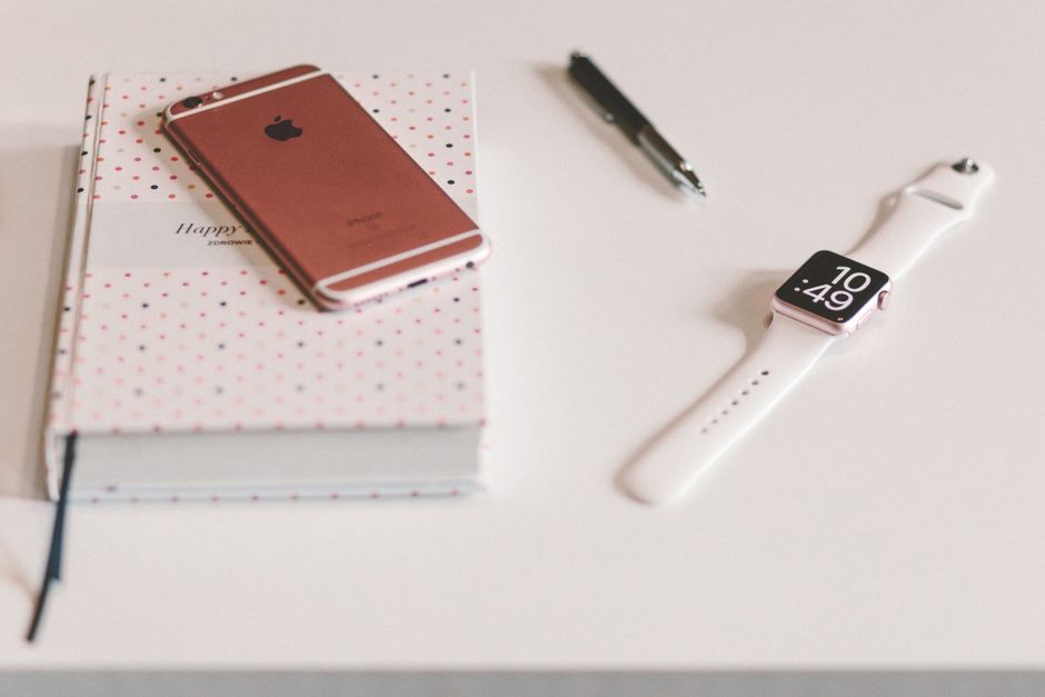 A minimalist desk featuring a smartwatch, smartphone, pen, and notebook for tech-savvy professionals.