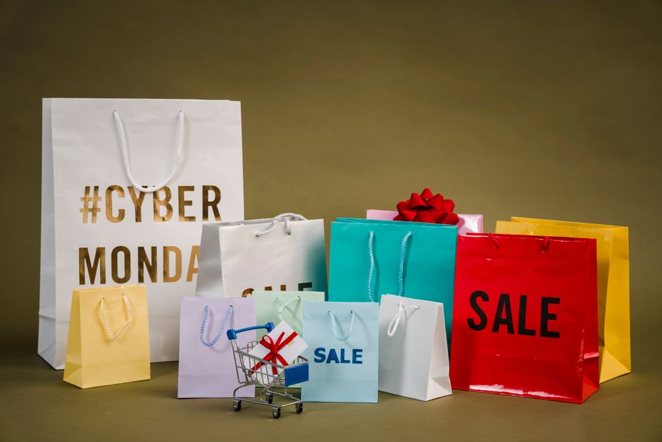 Colorful shopping bags with Cyber Monday and sale text, featuring a mini cart with gifts.