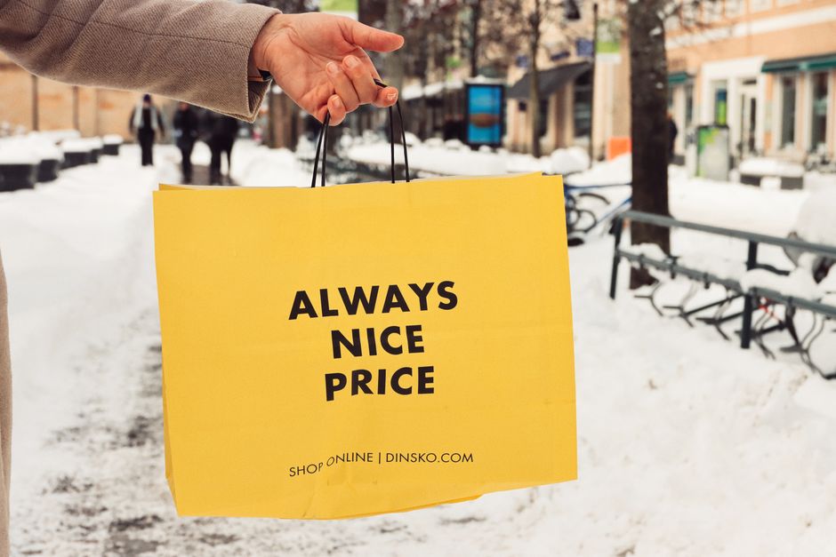 A person holding a yellow paper bag on a snowy street in Jönköping, Sweden during winter.