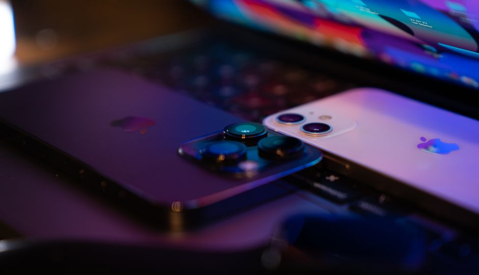Close-up image of two modern smartphones placed on a laptop keyboard, highlighting technology design.