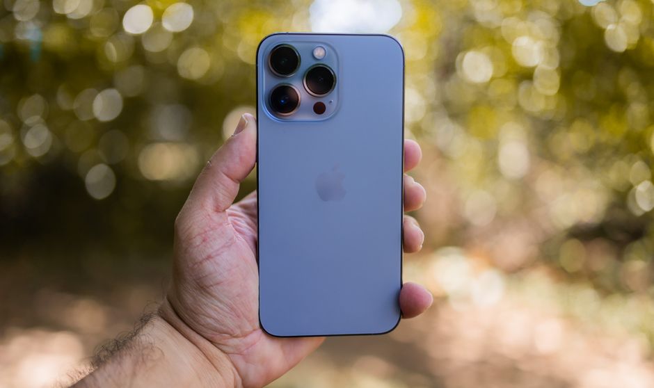 A hand holding a smartphone with blurred greenery background, perfect for technology themes.